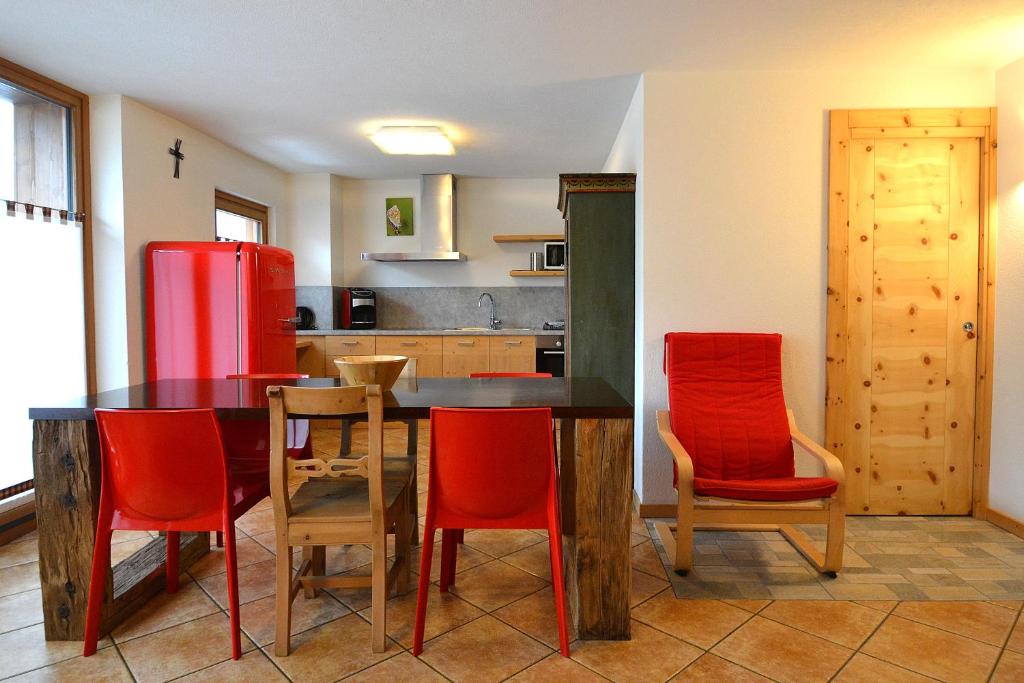 una cucina con tavolo, sedie e frigorifero rosso di Appartamenti Calanda - Livigno Center a Livigno