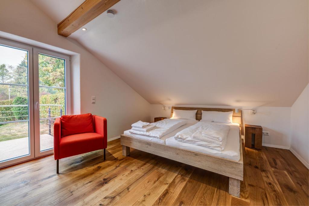 a bedroom with a bed and a red chair at Ferienhaus Tor zum Allgäu in Vogt