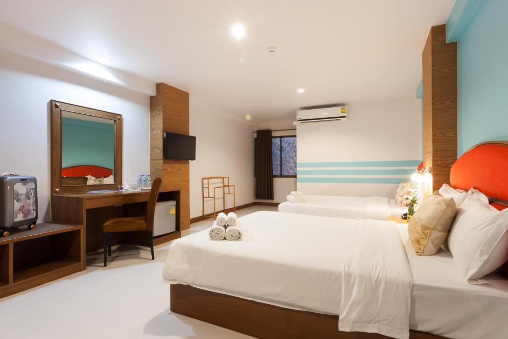 A spacious-looking room with two large beds, a dressing desk and a curtained window.