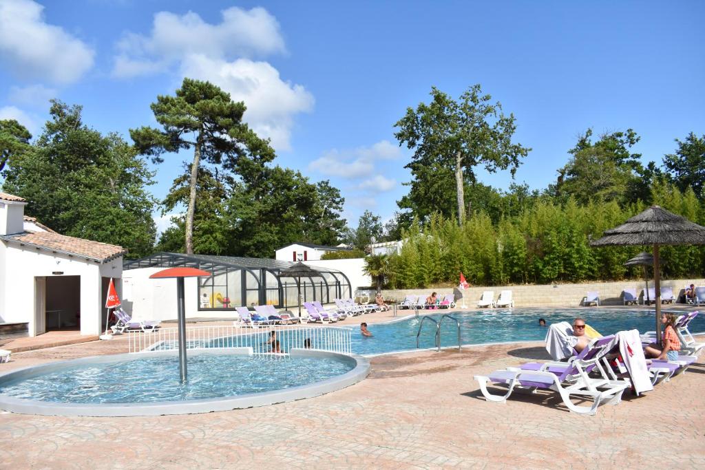 a swimming pool with chairs and people in a resort at Camping Les Pins de Sel in Saint-Augustin