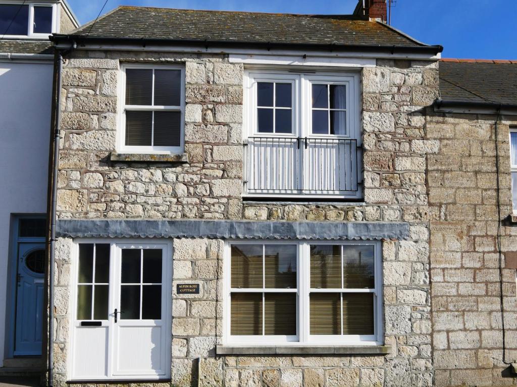 a stone house with white windows and a balcony at Alpen Rose Cottage in Portland