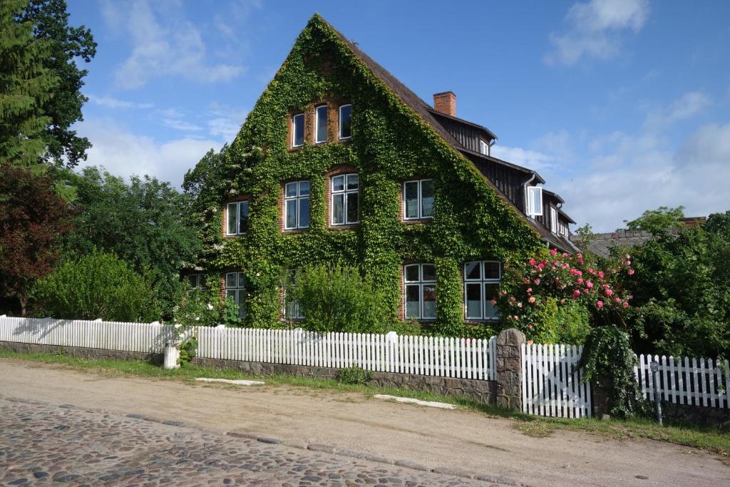 an ivy covered house with a white fence at Gemütliche Premium Öko Ferienwohnung in Resthof, super ausgestattet, keine Handwerker und Monteure in Sterley