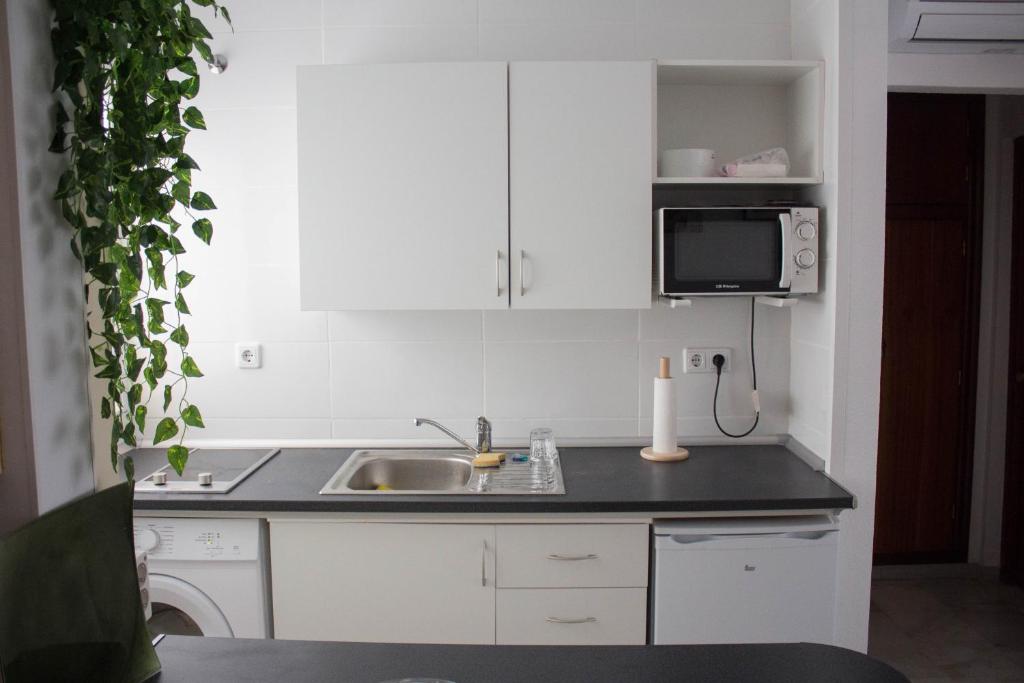 kuchnia z białymi szafkami, zlewem i kuchenką mikrofalową w obiekcie centrico apartamento nuevo, zona corte ingles w Maladze
