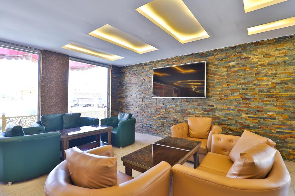 a lobby with couches and tables and a brick wall at Esfrine Hotel Apartment in Tabuk