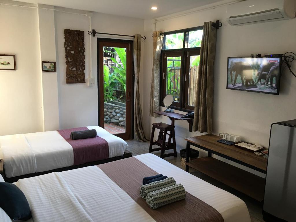 a hotel room with two beds and a television at Kingfisher House in Sangkhla Buri