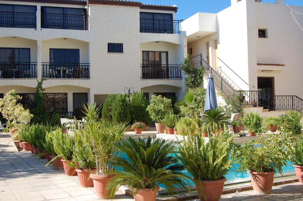 ein Gebäude mit Topfpflanzen vor einem Pool in der Unterkunft Nicos & Olympia Apartments in Polis Chrysochous