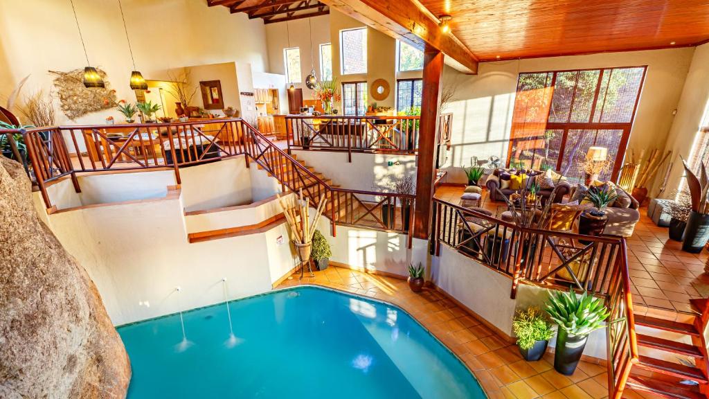 an indoor swimming pool in a house with a staircase at Ulwazi Rock Lodge in Hazyview