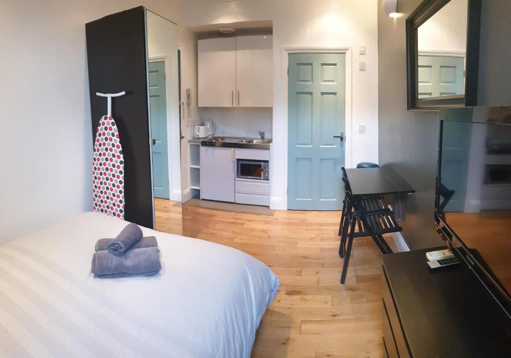 a bedroom with a white bed and a kitchen at Stylish Studio Room in Brixton - E in London