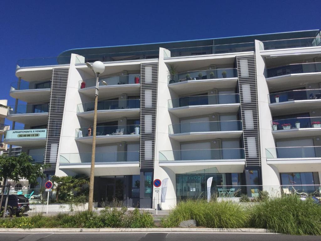 - un grand immeuble blanc avec un parking dans l'établissement La BAULE T3 - Face Mer, à La Baule