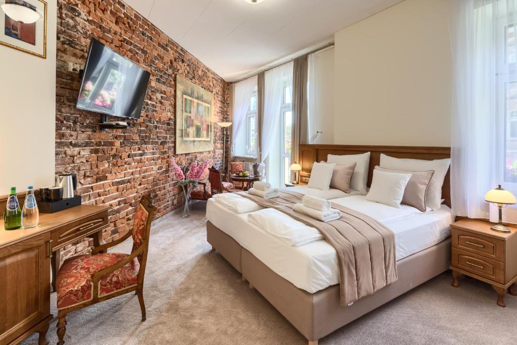 a bedroom with a large bed and a brick wall at Apartamenty Pod Baranem in Krakow