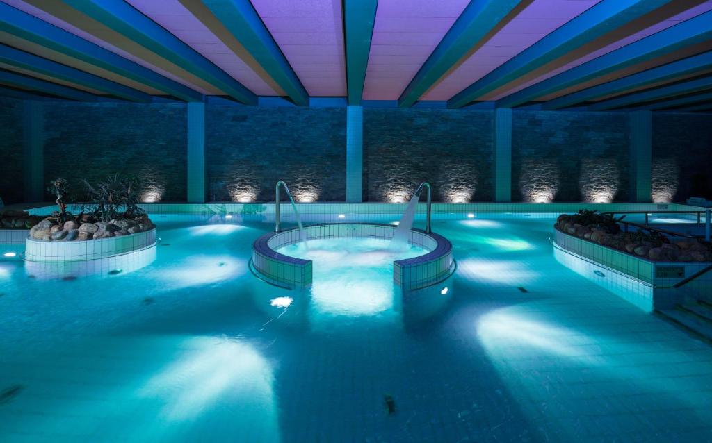 a swimming pool with two hot tubs in a building at Lapland Hotels Saaga in Ylläsjärvi