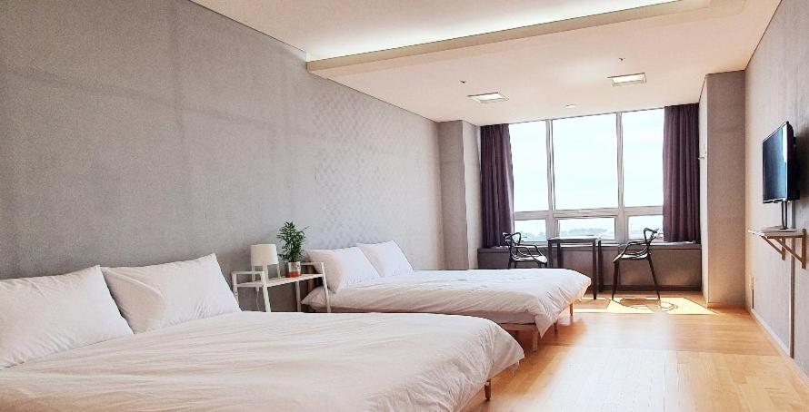 um quarto de hotel com duas camas e uma televisão em Treehouse em Incheon