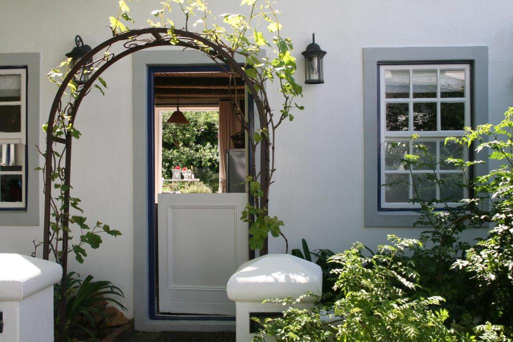 an archway in front of a house with plants at The Cottage on 55 in Franschhoek