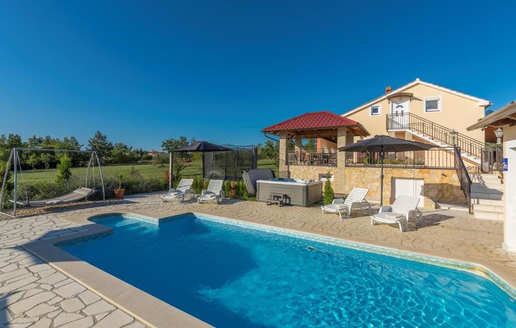 a swimming pool in a yard with chairs and a house at Villa Ivda in Porec Area in Nova Vas