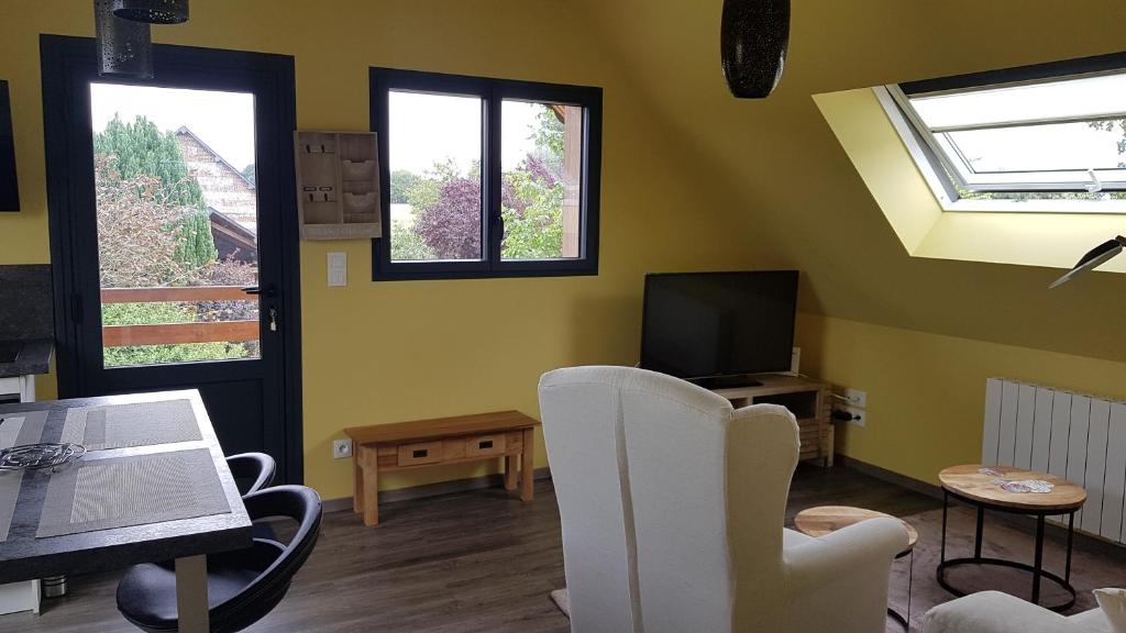 a living room with white chairs and a television at nid cauchois in Betteville