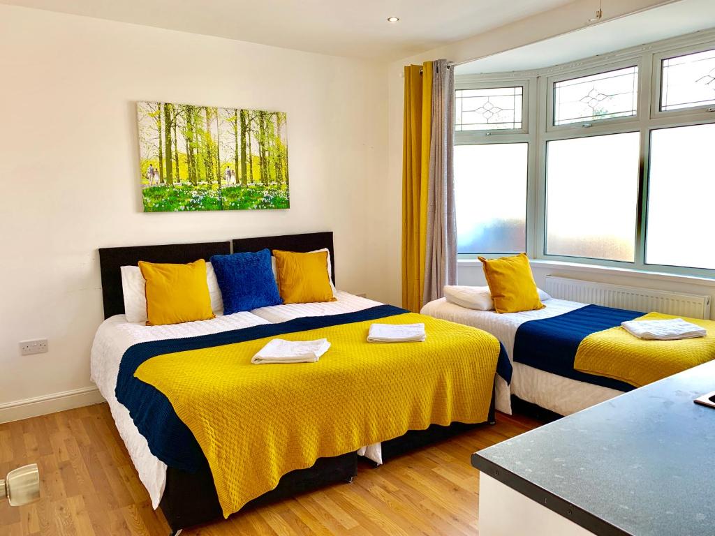 - 2 lits dans une chambre jaune et bleue dans l'établissement 4 Bedrooms, 3 Baths, Full Kitchen and Lounge, Garden, Free Parking, à Londres