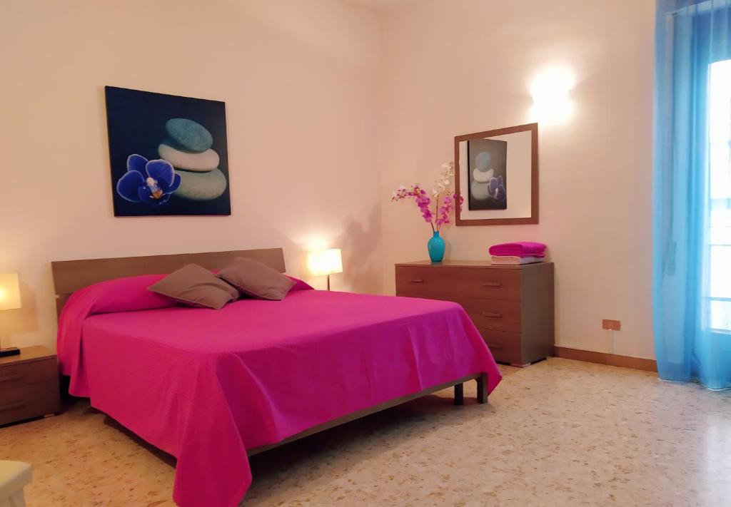 ein Schlafzimmer mit einem rosa Bett mit einer rosa Decke in der Unterkunft La casa di Francesca in Reggio di Calabria