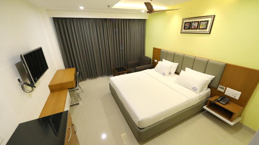a hotel room with a bed and a television at Hotel Sri Ram Grand in Vijayawāda