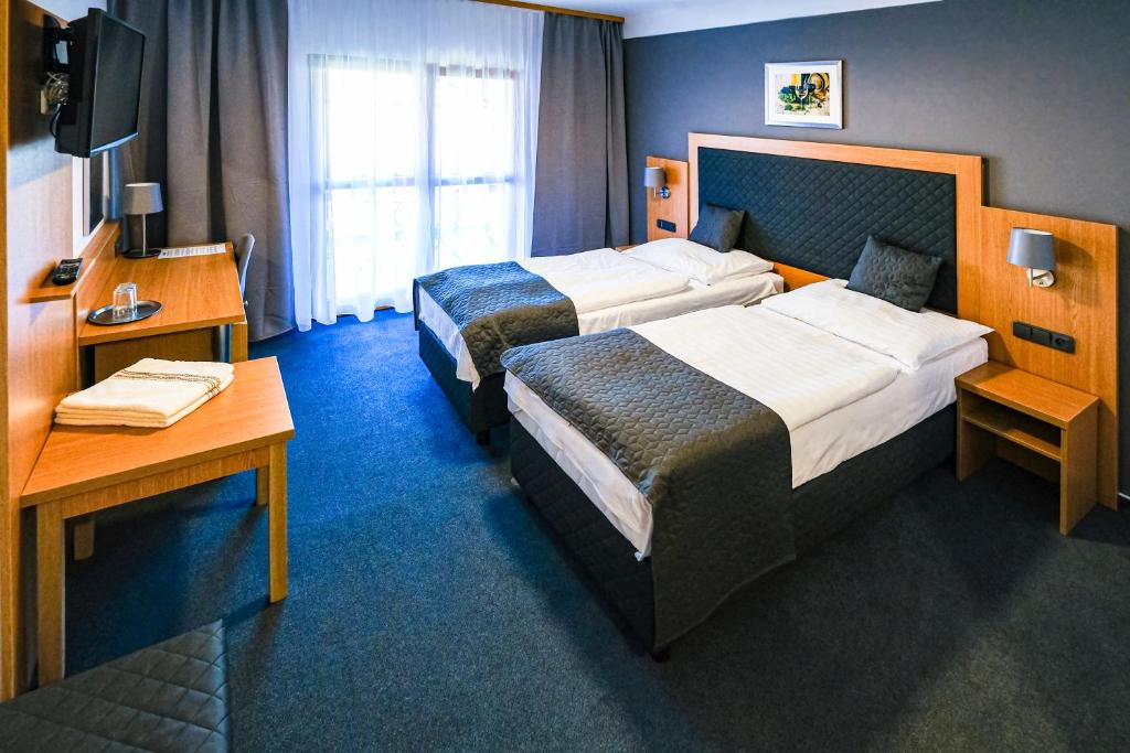 a hotel room with two beds and a desk at Hotel Rustikal in Hustopeče