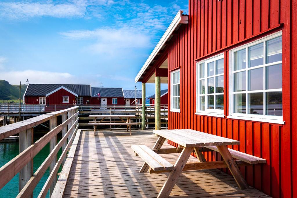 a red building with a picnic table on a dock at Lofoten Seaview Villa in Leknes