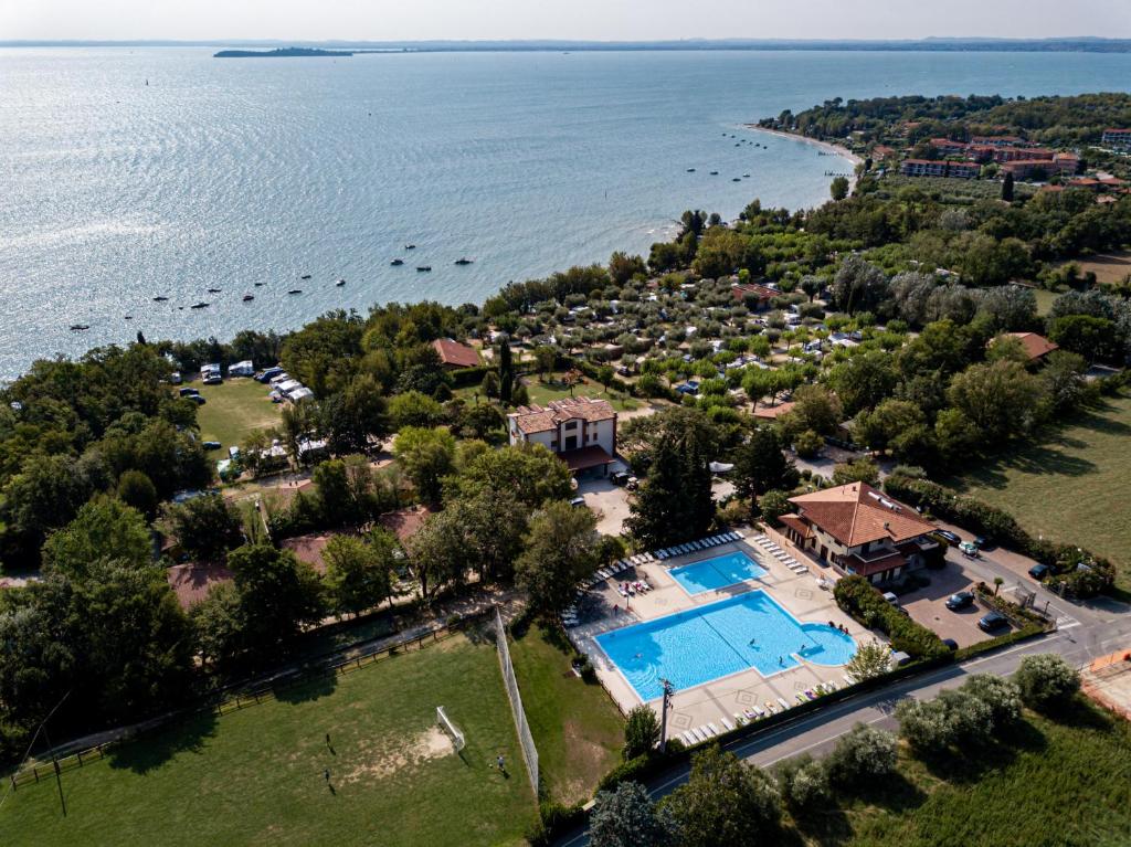 an aerial view of a house with a pool and the water at Camping Zocco in Manerba del Garda