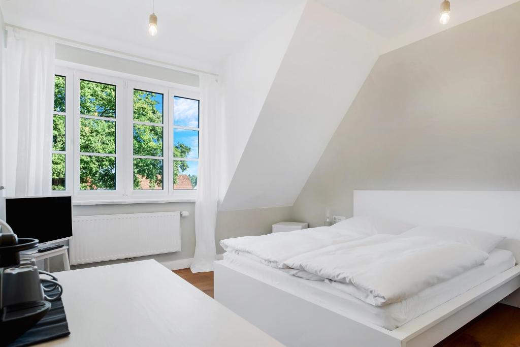 a white bedroom with a bed and a window at Ferien Hohes Elbufer in Schnakenbek