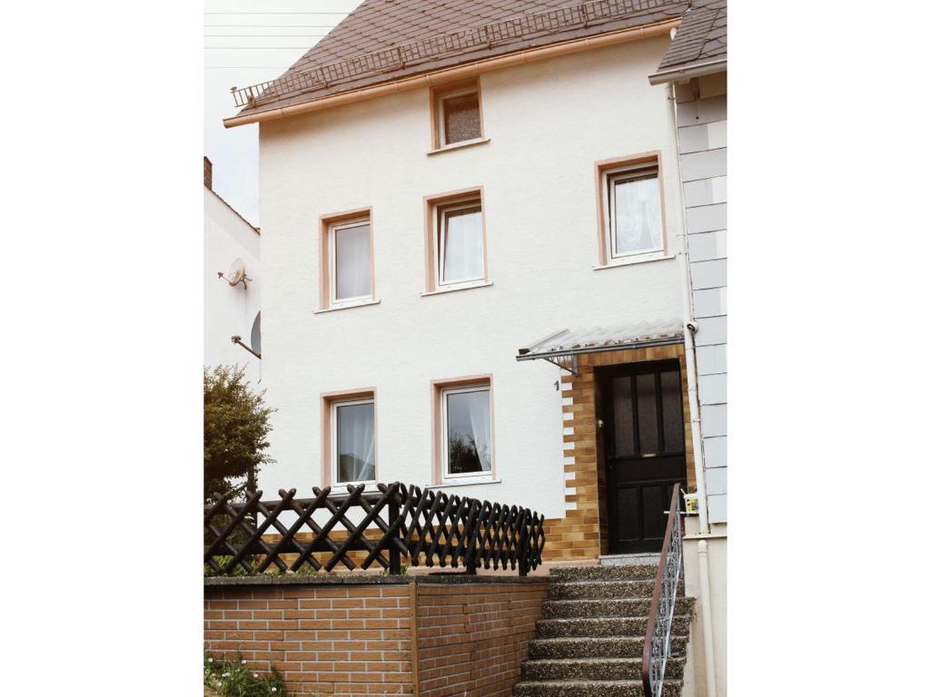 a white house with a brick fence at Haus Mersche in Gösenroth