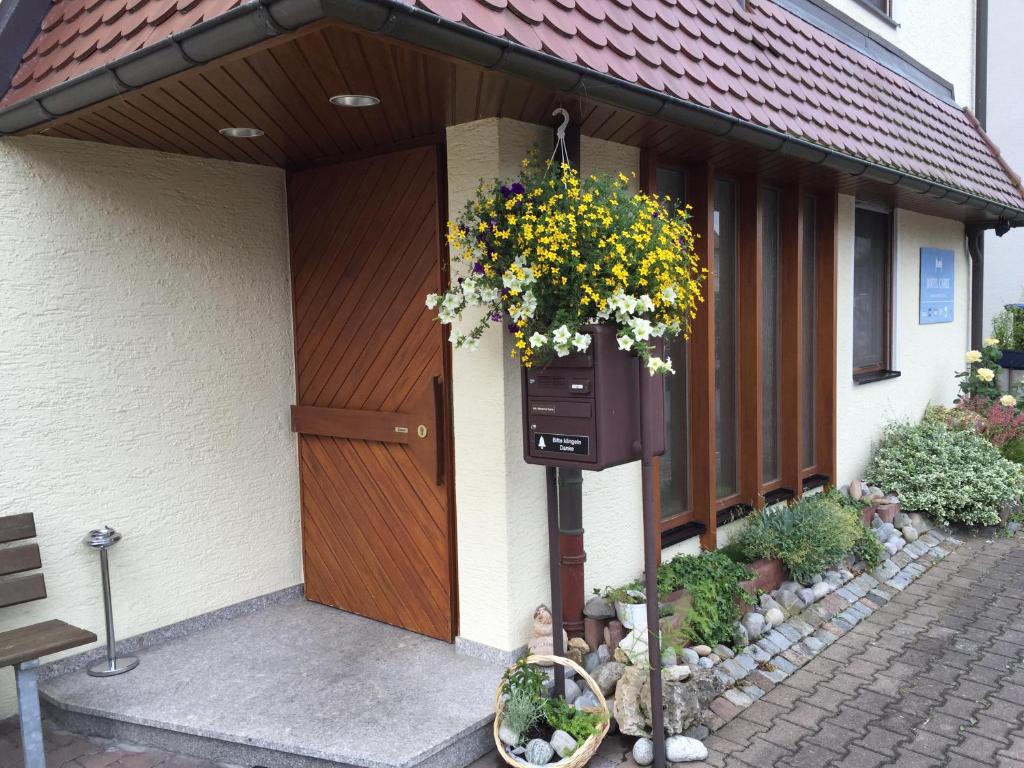 une maison avec une porte en bois et une corbeille de fleurs dans l'établissement Hotel Carle, à Deizisau
