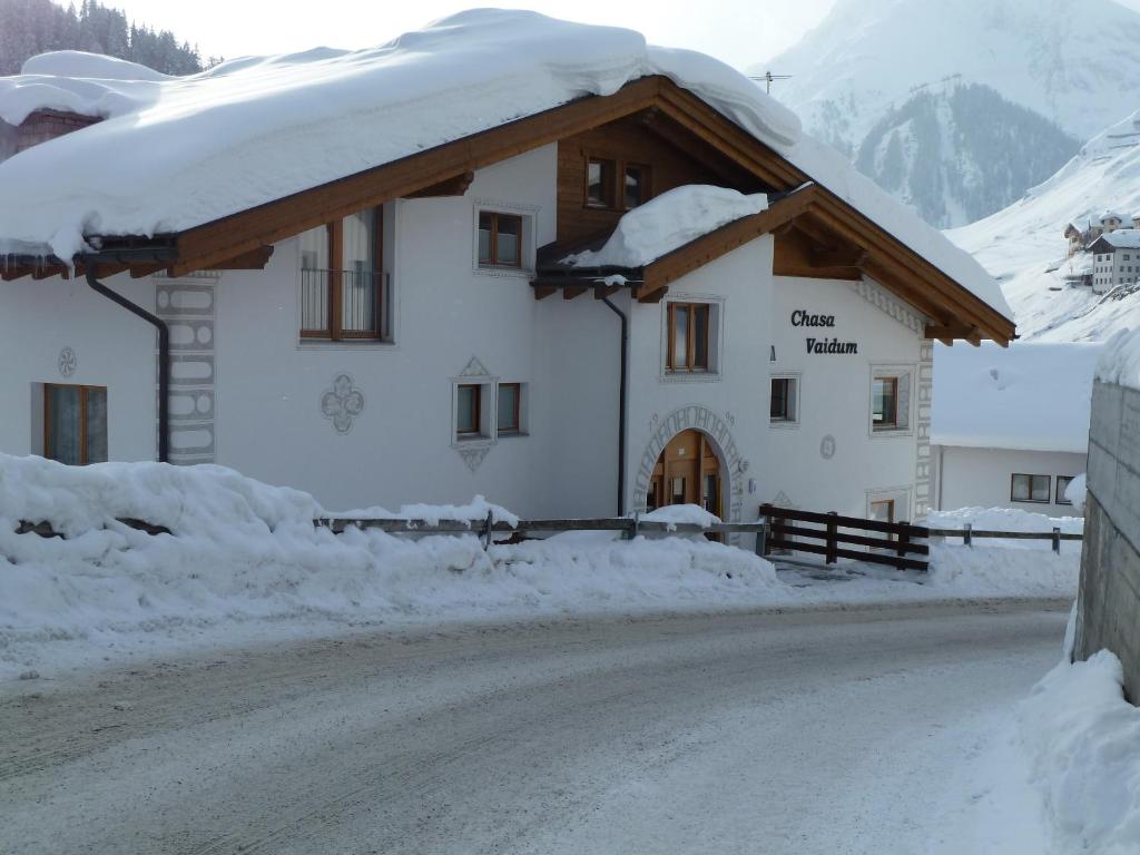 a building covered in snow on a snowy road at Chasa Vaidum by MEIN SAMNAUN - MOUNTAIN HOMES in Samnaun