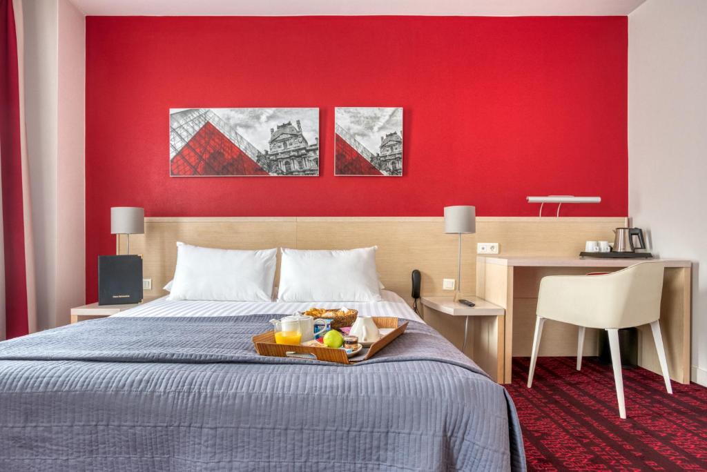 ein Hotelzimmer mit einem Bett und einer roten Wand in der Unterkunft Hotel Le Richemont in Paris