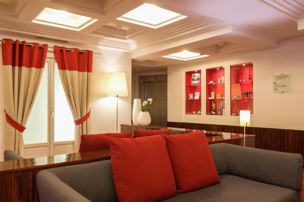ein Wohnzimmer mit einem Sofa und roten Kissen in der Unterkunft Hotel Le Richemont in Paris