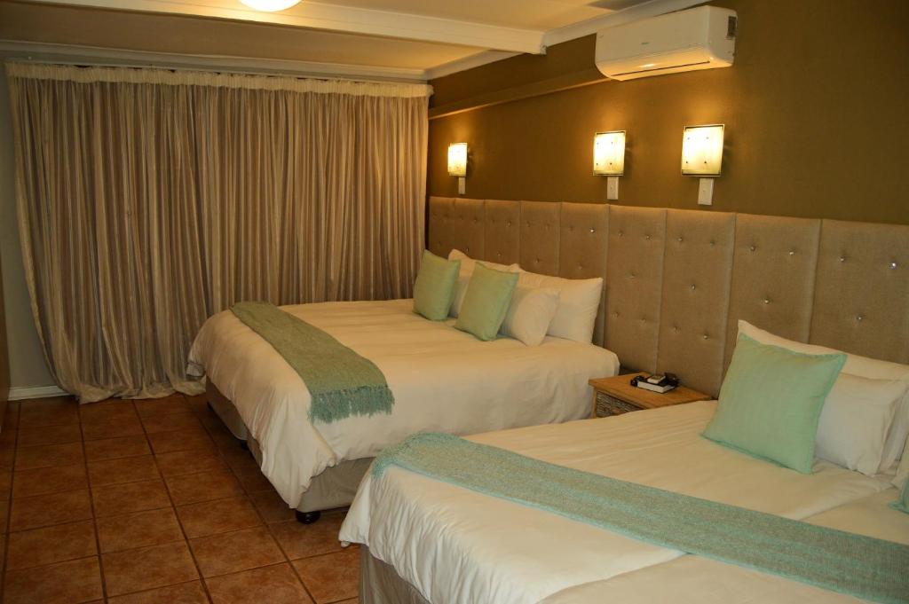 a hotel room with two beds with green and white pillows at Crystal Rose Lodge & Spa in Krugersdorp