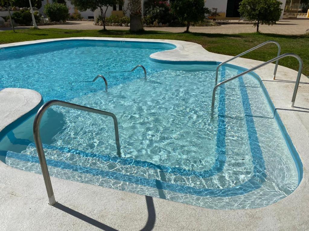 una piscina con agua azul y barras metálicas en Apartamentos Roquetas Beach, en Roquetas de Mar