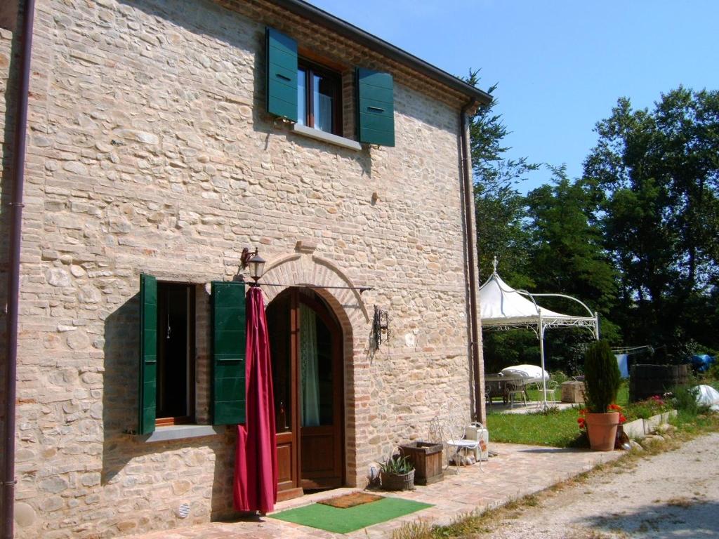 a stone building with green shutters and red umbrellas on it at B&B Mulini Venturi in Saludecio