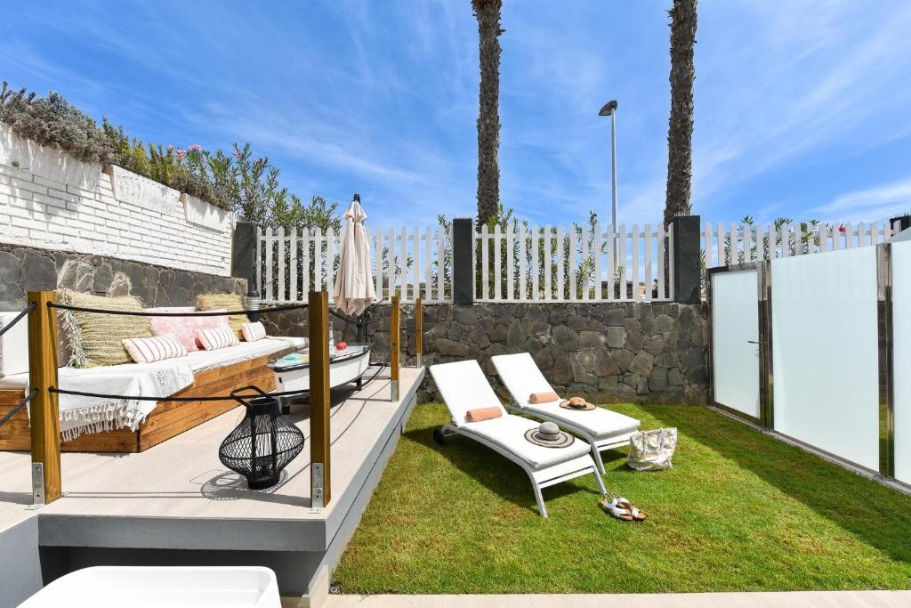a patio with white furniture and a fence at Maspalomas Beach apartment La Charca III in Maspalomas