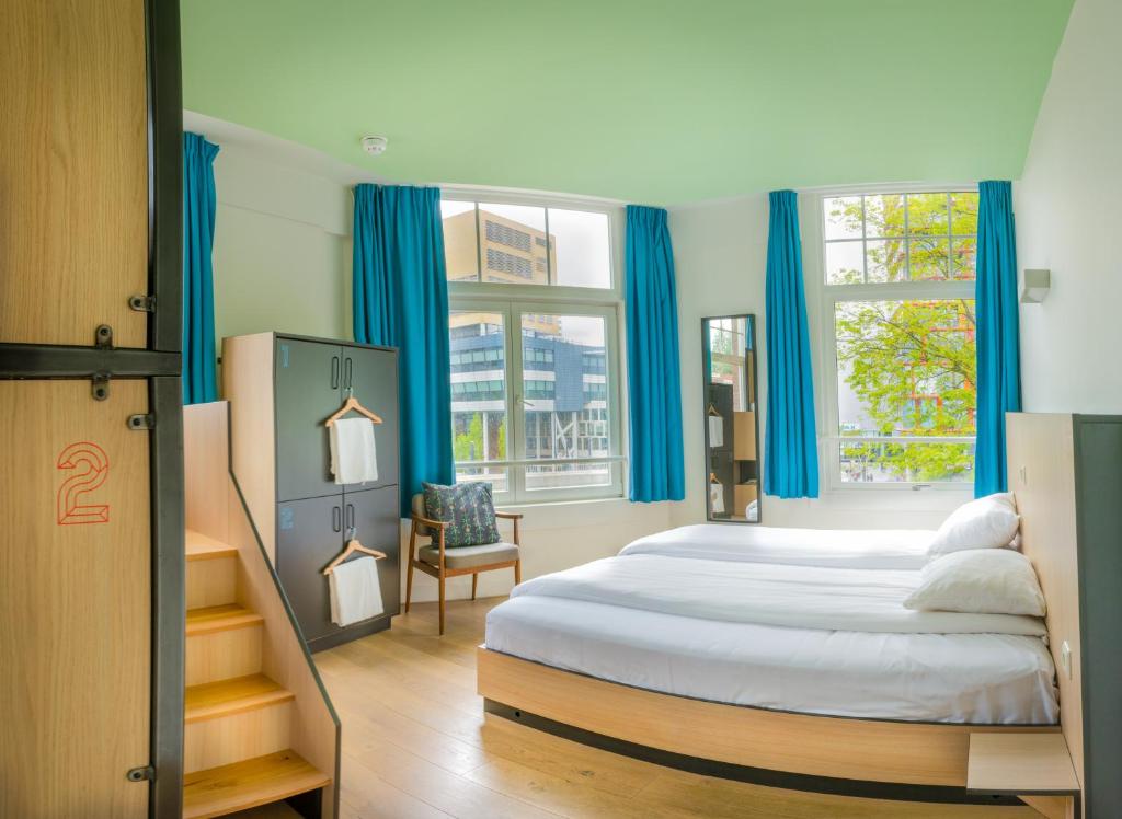 1 dormitorio con 1 cama grande y cortinas azules en Sparks Hostel, en Róterdam