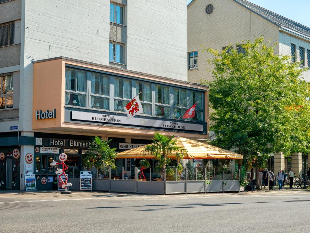 Un edificio in una strada con gente che cammina davanti di Hotel Blumenstein Self-Check In a Frauenfeld