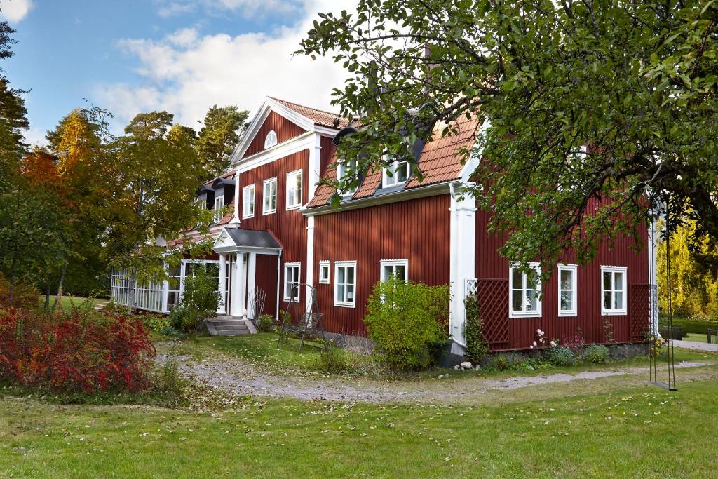 una casa roja con ventanas blancas y un árbol en Red Haven Cottage, en Edsbruk