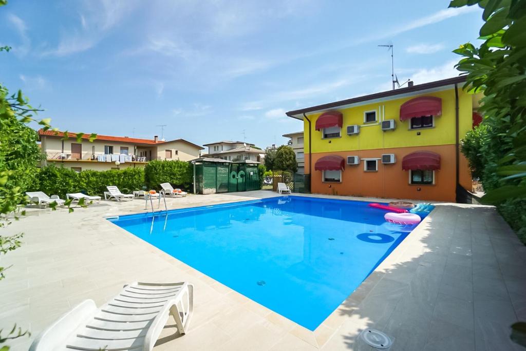 a swimming pool with chairs and a building at Villa Carola in Bibione