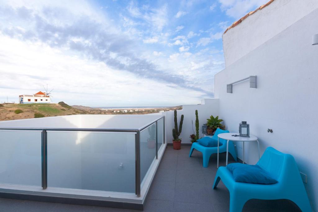 a balcony with blue chairs and a table at Sea View Apartment Carrapateira in Carrapateira