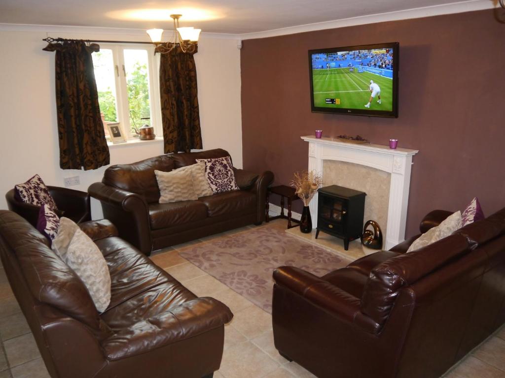 sala de estar con sofás de cuero y TV en The Shakespeare Lodge - Sleeps up to 12 - HOT TUB en Stratford-upon-Avon