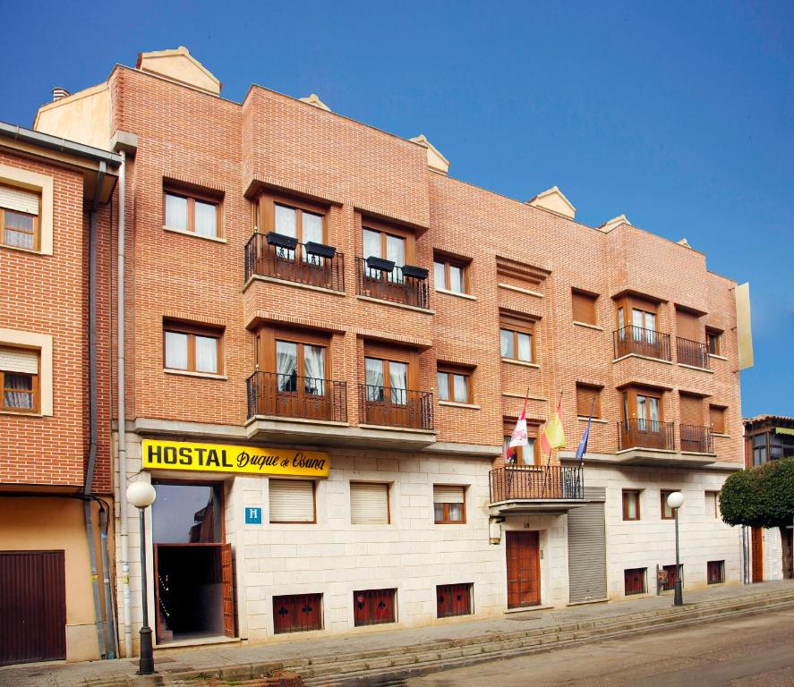 un gran edificio de ladrillo rojo con balcones. en Duque De Osuna en Medina de Rioseco