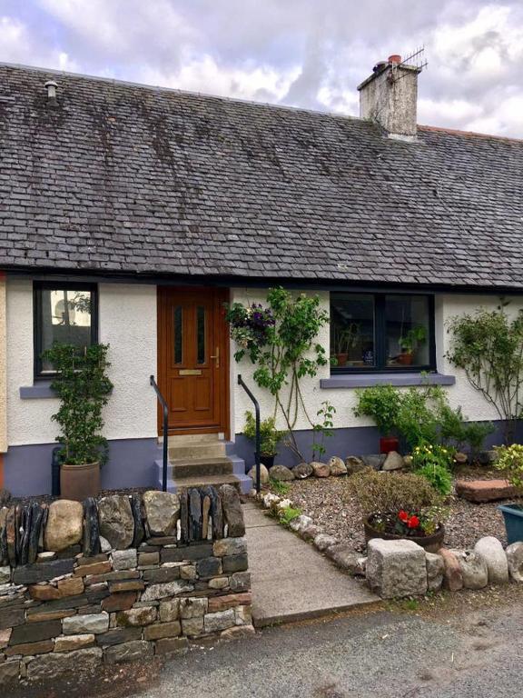 a white house with a brown door and windows at Holly Cottage in Glencoe