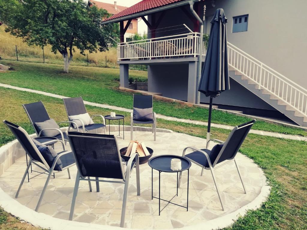 un grupo de sillas y una sombrilla en un patio en Artisan House Meraki en Udbina
