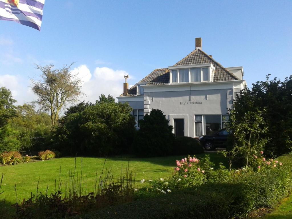 a white house with a flag in front of it at Hof Christina Vakantiewoningen in Vrouwenpolder