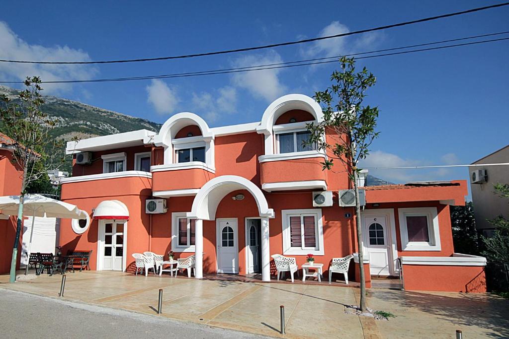 een oranje gebouw met tafels en stoelen ervoor bij Apartments Kruna Jovanović in Sutomore