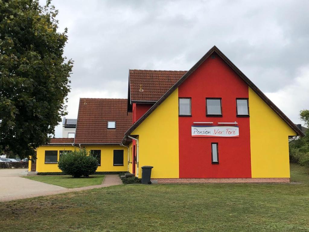 ein rotes gelbes und rotes Haus mit einem Schild darauf in der Unterkunft Pension ,,Vier Tore'' in Neubrandenburg