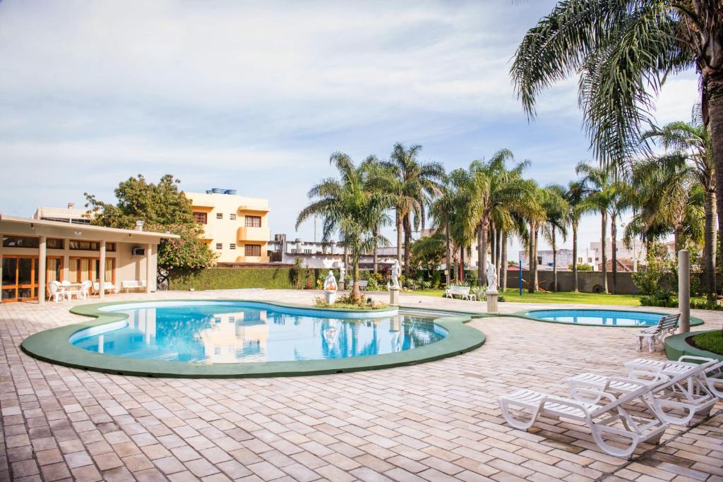 a swimming pool with palm trees and a resort at Hotel São Luiz in São Gabriel