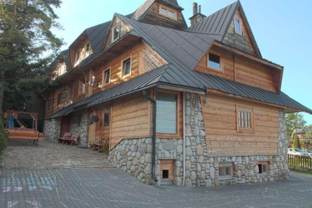 a large wooden house with a gambrel roof at Pokoje Gościnne Za Sichłą in Murzasichle