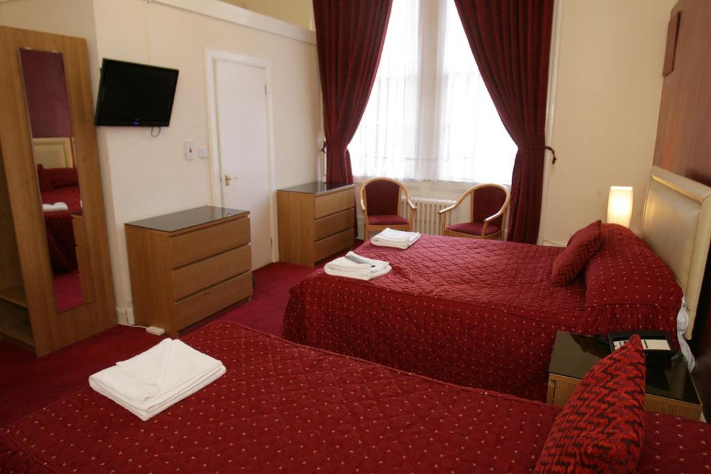 a hotel room with two beds and a mirror at Clifton Hotel in Glasgow